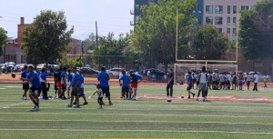 Youth and adult flag football players warm up on the field before the Change for De'Quan community football event in Denver, Colorado.
