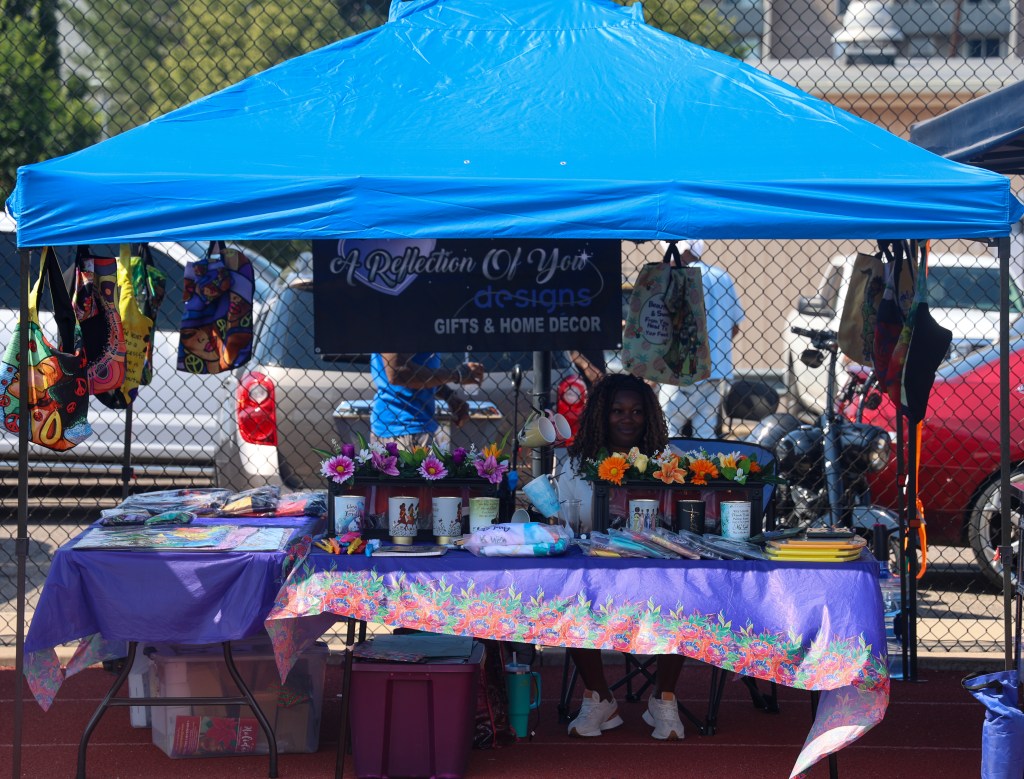 The A Reflection of You Designs vendor booth displays handmade gifts, floral arrangements, home décor, and custom merchandise during the Change for De'Quan event.