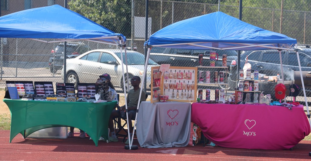 Local vendors display sunglasses, jewelry, custom drinkware, accessories, and handmade merchandise during the Change for De'Quan community event in Denver.