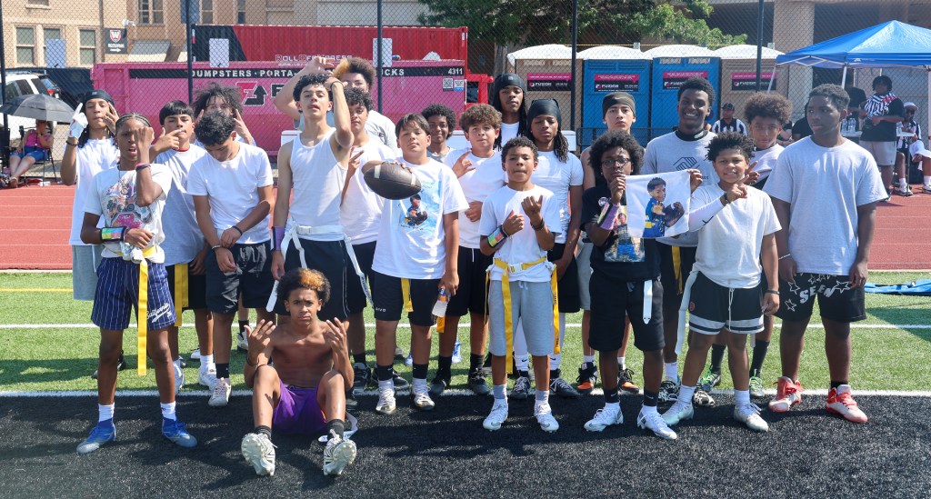 Members of Team Squizzy pose for a group photo after winning the Change for De'Quan 5280 Influencer Flag Football Game in Denver, with several players displaying memorial images of De'Quan.
