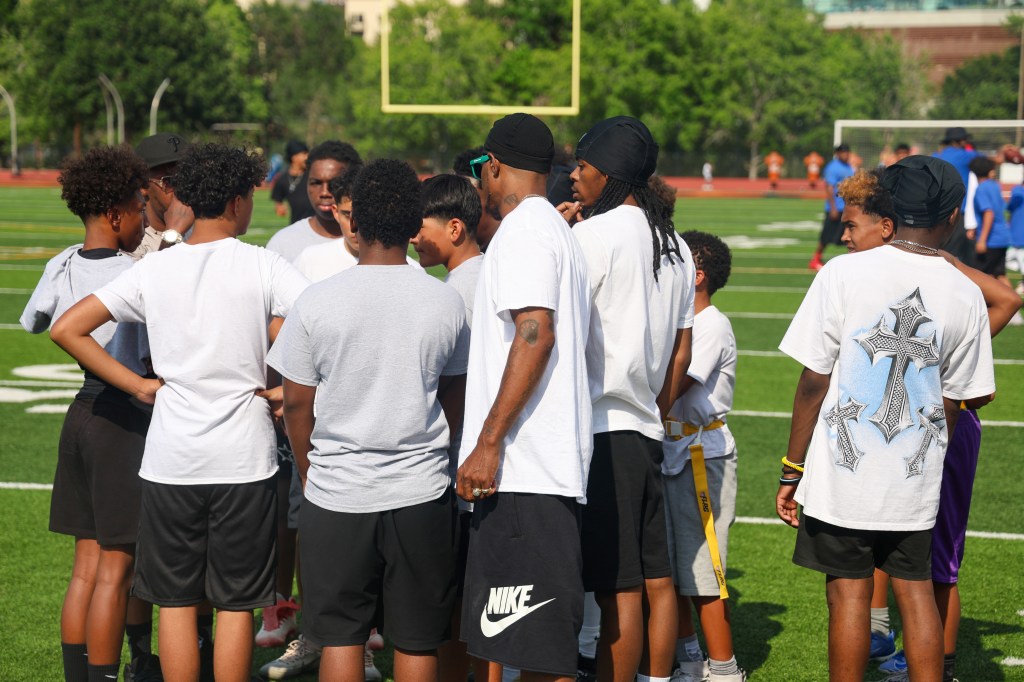 Youth flag football players and coaches gather in a pregame huddle on the field during the Change for De'Quan community event in Denver, Colorado.