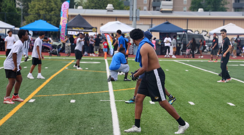 Youth flag football players line up before the snap as spectators and local vendors watch from the sidelines during the Change for De'Quan event in Denver.